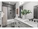 Stylish bathroom featuring dual vanities, modern fixtures, sleek gray tile, and a shower-tub combination at 3937 Plainview Rd, Charlotte, NC 28208
