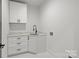 Bright laundry room featuring white cabinetry, a sleek black faucet, and a modern marble floor at 3937 Plainview Rd, Charlotte, NC 28208