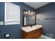 Bathroom featuring a dark-stained vanity, framed mirror with decorative lighting, and a neutral color palette at 402 Beaver Dam Church Rd, Shelby, NC 28152