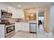 Well-lit kitchen with white cabinets, stainless steel appliances, mosaic backsplash, and gray wood-look tile flooring at 5909 Cougar Ln, Charlotte, NC 28269