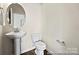 Stylish powder room featuring a pedestal sink, modern toilet, and elegant mirror at 626 Wabash Ave # 6, Charlotte, NC 28208