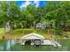 View of boat dock with a boat and house in the background nestled among the trees at 698 Normandy Rd, Mooresville, NC 28117
