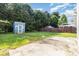 Large backyard with green grass, mature trees, and a blue storage shed at 7643 Monarch Birch Ln, Charlotte, NC 28215