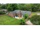 Aerial view of brick home with a patio seating area surrounded by a lush green lawn and mature trees at 115 Fox Run Dr, Fort Mill, SC 29715