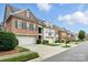 Charming row of townhomes featuring brick and white exteriors, well-maintained landscaping, and attached garages at 11724 Easthampton Cir, Charlotte, NC 28277