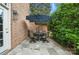 Outdoor patio with a round table set under an umbrella, surrounded by lush greenery and a brick wall at 11724 Easthampton Cir, Charlotte, NC 28277