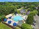 Aerial view of a community pool with multiple swimming lanes, lounge chairs, umbrellas, and lush greenery at 11724 Easthampton Cir, Charlotte, NC 28277
