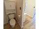 Compact bathroom with a toilet, storage cabinet, and gold hardware, complemented by tile flooring at 1410 4Th Street Nw Dr # 303, Hickory, NC 28601