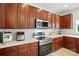 A close view of modern stainless steel appliances, cherry cabinets, and tile backsplash at 15508 Normans Landing Dr, Charlotte, NC 28273