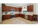 Well-lit kitchen boasts cherry wood cabinets, stainless steel appliances, and tile backsplash at 15508 Normans Landing Dr, Charlotte, NC 28273