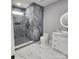 Modern bathroom featuring marble-style tile, glass-enclosed shower, and a stylish vanity with a lighted round mirror at 15818 Sparrowridge Ct, Charlotte, NC 28278