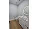 Contemporary half-bathroom featuring white vanity with round mirror and hardwood flooring, offering a modern aesthetic at 15818 Sparrowridge Ct, Charlotte, NC 28278