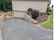 Wide driveway to a downstairs garage with a beautifully landscaped retaining wall and yard at 1764 Pipers Ridge Nw Cir, Conover, NC 28613