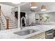 Close up of kitchen island featuring marble countertop and sink with open view to living room and wooden staircase at 319 Catawba Ave, Rock Hill, SC 29730
