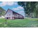 Home exterior featuring a deck, grassy yard, and mature trees under a bright sky at 5437 Mallard Ln, Gastonia, NC 28052