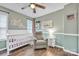 Well-lit Bedroom with crib, chair, ceiling fan, wood floors, and picture window at 5476 Twelve Oak Ln, Conover, NC 28613