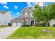 Charming two-story home featuring a stone and gray shingle facade, a well-manicured lawn and a two-car garage at 586 Brookhaven Dr, Fort Mill, SC 29708