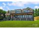 Expansive rear exterior of home with covered porch, stone accents, and well-manicured lawn at 5985 Natoma Rd, Clover, SC 29710