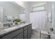 Bright bathroom with double vanity, granite countertop, soft gray cabinets, and a bathtub with white shower curtain at 658 Gardenbrook Trl, Belmont, NC 28012