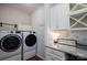Well-organized laundry room features granite countertops and modern washer and dryer at 658 Gardenbrook Trl, Belmont, NC 28012