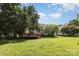 Large backyard with a spacious lawn, mature trees, and a wooden deck attached to the house at 6603 Brenock Ln, Charlotte, NC 28269