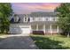 Charming two-story traditional home with a welcoming front porch, two-car garage, and landscaped front yard under a colorful sunset at 6603 Brenock Ln, Charlotte, NC 28269