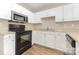 Functional kitchen featuring white cabinets, a black oven and microwave, and a stainless steel sink at 6603 Brenock Ln, Charlotte, NC 28269
