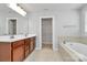 Bathroom featuring double sinks, a soaking tub, and closet access at 7079 Waterwheel Sw St, Concord, NC 28025