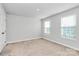 Bright, carpeted bedroom offers neutral tones, with natural light from two large windows at 7079 Waterwheel Sw St, Concord, NC 28025