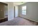 Bedroom with neutral carpet, light gray walls, bright windows, and open doorway at 7315 Fig Ln, Charlotte, NC 28215