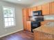 Bright kitchen featuring wood cabinets, black appliances, and laminate floors at 7315 Fig Ln, Charlotte, NC 28215