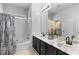 Modern bathroom with double vanity featuring stylish black cabinets, marble countertops, and tub with shower at 9704 Grier Springs Ln, Charlotte, NC 28213