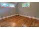 Empty bedroom showcasing gleaming hardwood floors, neutral walls, white trim, and bright windows at 1017 Andover Rd, Charlotte, NC 28211