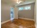 Empty bedroom showcasing gleaming hardwood floors, neutral walls, white trim, and doorway to kitchen at 1017 Andover Rd, Charlotte, NC 28211