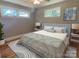 Cozy bedroom featuring hardwood floors, windows, ceiling fan, and a bed with a blue frame and patterned comforter at 1017 Andover Rd, Charlotte, NC 28211