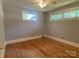 Empty bedroom showcasing gleaming hardwood floors, neutral walls, white trim, and bright windows at 1017 Andover Rd, Charlotte, NC 28211