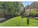 A lush green backyard featuring a deck, mature trees, and landscaped garden beds at 10320 Lemington Dr, Mint Hill, NC 28227