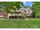 Beautiful brick two-story home with manicured lawn and mature trees, featuring a stone archway at the entrance at 10320 Lemington Dr, Mint Hill, NC 28227