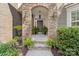 Inviting front door framed by a stone archway, decorative plants, and outdoor lighting at 10320 Lemington Dr, Mint Hill, NC 28227