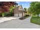 Large three-car garage with a spacious driveway and side yard surrounded by lush greenery at 10320 Lemington Dr, Mint Hill, NC 28227