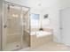Inviting bathroom boasts a glass enclosed shower, soaking tub, and neutral tile at 10320 Lemington Dr, Mint Hill, NC 28227