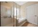 Bright bathroom with a glass shower, soaking tub, and window at 1103 Phar Lap Dr, Indian Trail, NC 28079