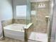 Close-up of a soaking tub and shower in a bright bathroom with neutral tile at 11109 Pond Valley Ct, Charlotte, NC 28269