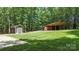 Backyard with outbuildings including a garage and long shed with a covered patio area at 1556 Stanley Lucia Rd, Mount Holly, NC 28120
