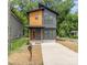 Modern two-story home featuring gray and natural wood siding, a stylish front door, and a concrete driveway at 177 Georgia Sw St, Concord, NC 28025