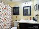 Cozy bathroom featuring a dark vanity, framed mirror, matching wall cabinet, and decorative fall-themed shower curtain at 2174 Eastview Rd, Rock Hill, SC 29732