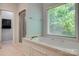 Bright bathroom featuring a jacuzzi tub under a window, separate shower, and white tile flooring at 2289 Veery Ln, Rock Hill, SC 29732