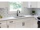 Close up of a modern kitchen sink and black fixtures with white cabinets and quartz counters at 2610 Fairgreen Dr, Gastonia, NC 28056