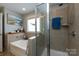 Bright bathroom featuring a soaking tub with tiled surround, separate glass shower, and modern fixtures at 298 Bridges Farm Rd, Mooresville, NC 28115