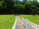 Green grassy backyard with a small fire pit and wooden foot bridge in a home for sale at 33343 Old Salisbury Rd, Albemarle, NC 28001